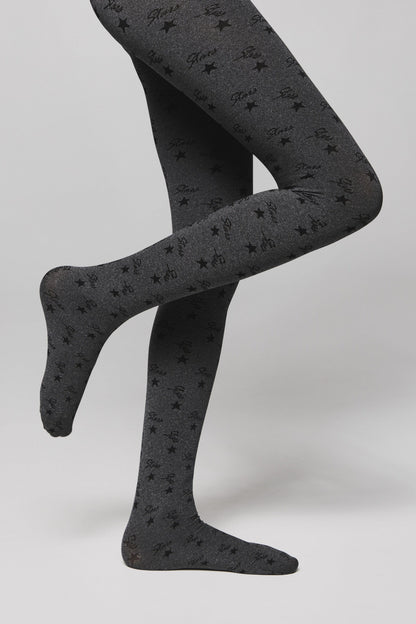 Gray tights with an all-over black star and cursive text pattern worn on the legs of a person against a neutral background.