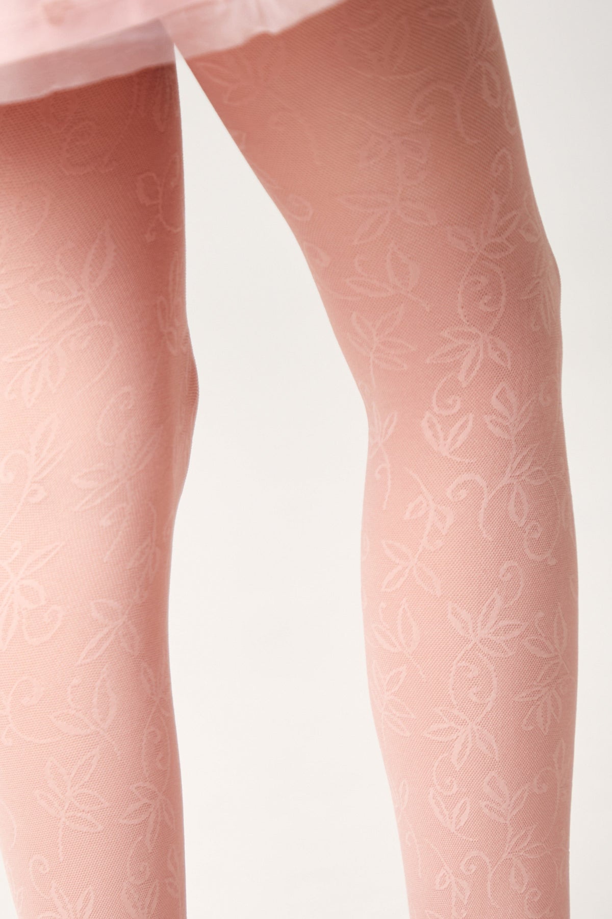 Light pink tights featuring an intricate tonal floral and vine pattern across the legs.