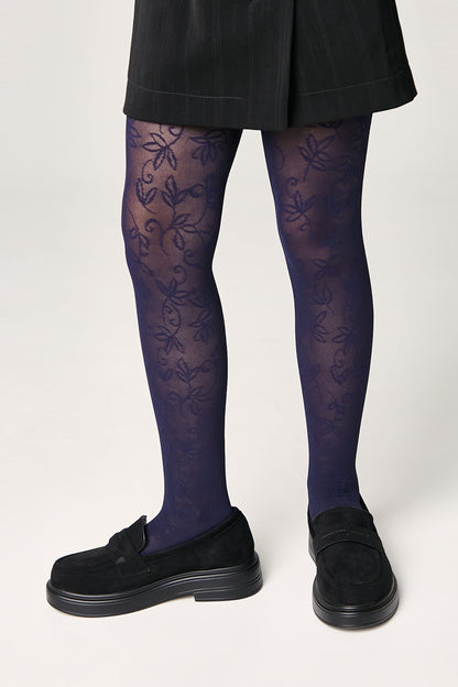 Blue tights featuring a delicate floral pattern worn with a black mini skirt and black platform loafers.
