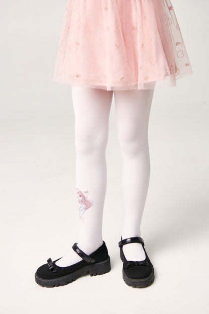 A pair of white tights featuring a small pink girl character graphic on the calf, worn by a child with a pink skirt and black flat shoes.