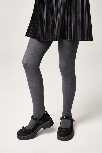 A pair of charcoal grey tights worn with a black pleated skirt and black Mary Jane shoes with thick rubber lug soles.