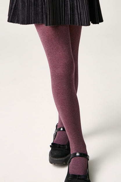 Burgundy opaque tights paired with a black pleated skirt and black Mary Jane shoes.