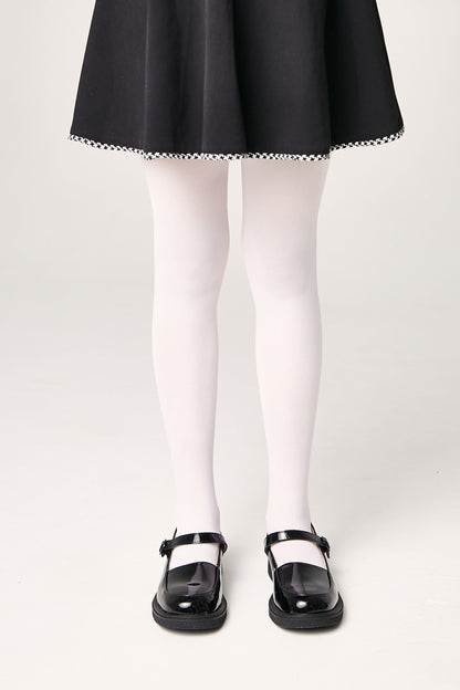 A pair of white opaque tights worn with a black flared skirt and black patent leather Mary Jane shoes.