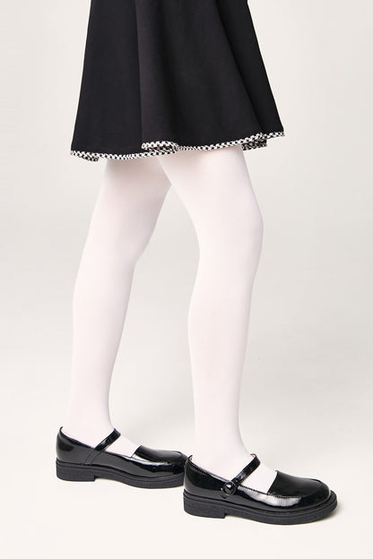 A person wearing a black flared skirt with a houndstooth-patterned hem, solid white tights, and black patent leather Mary Jane shoes against a plain off-white background.