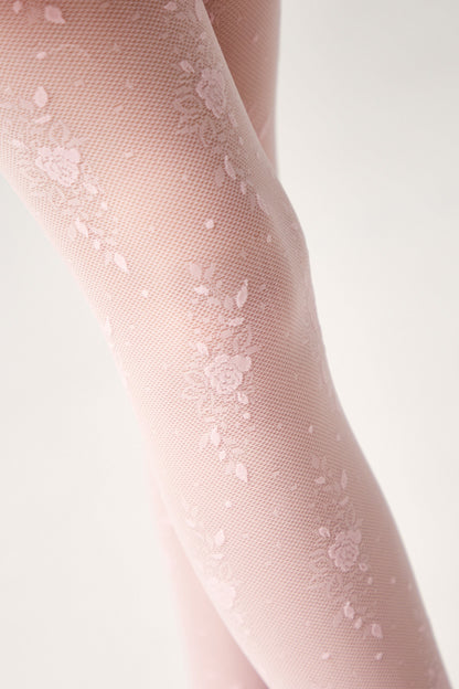 A close-up view of light pink floral patterned tights worn on legs against a plain white background.