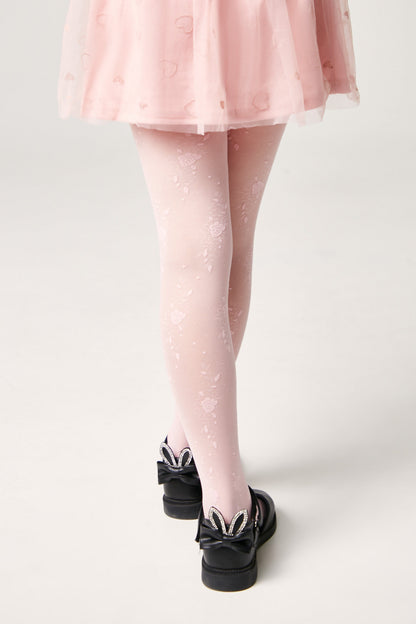 Light pink floral pattern tights worn under a light pink skirt, paired with black shoes featuring bunny-ear bows on the heels.