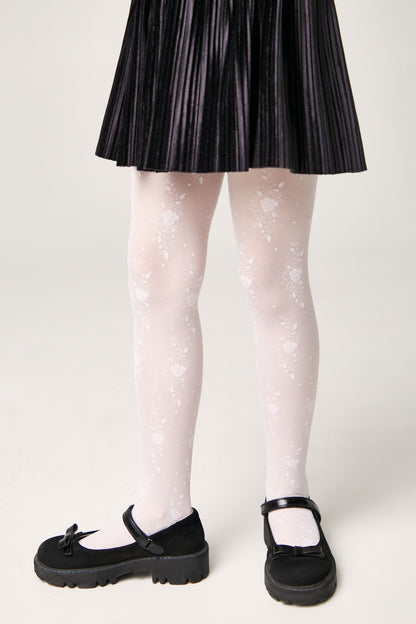 White tights with a delicate floral lace pattern worn under a black pleated skirt with black buckled mary jane shoes.