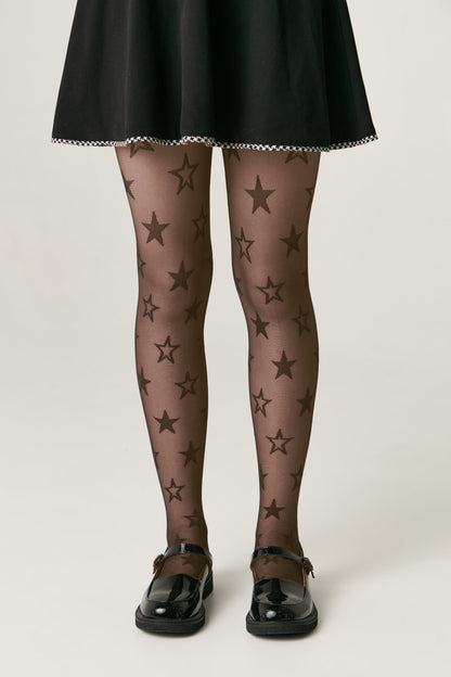 Sheer black tights featuring an all-over star pattern, worn under a black skirt with black Mary Jane shoes.