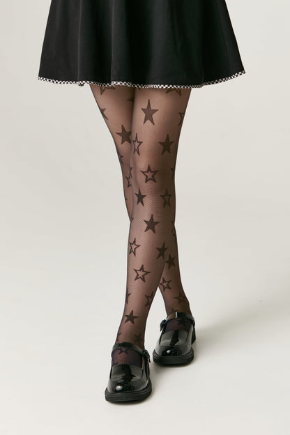 Sheer black tights patterned with dark grey stars, worn with a black skirt and glossy black Mary Jane shoes.