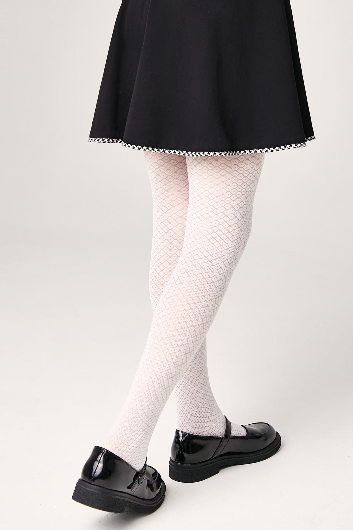 White patterned tights worn with a black skirt and black mary jane shoes.