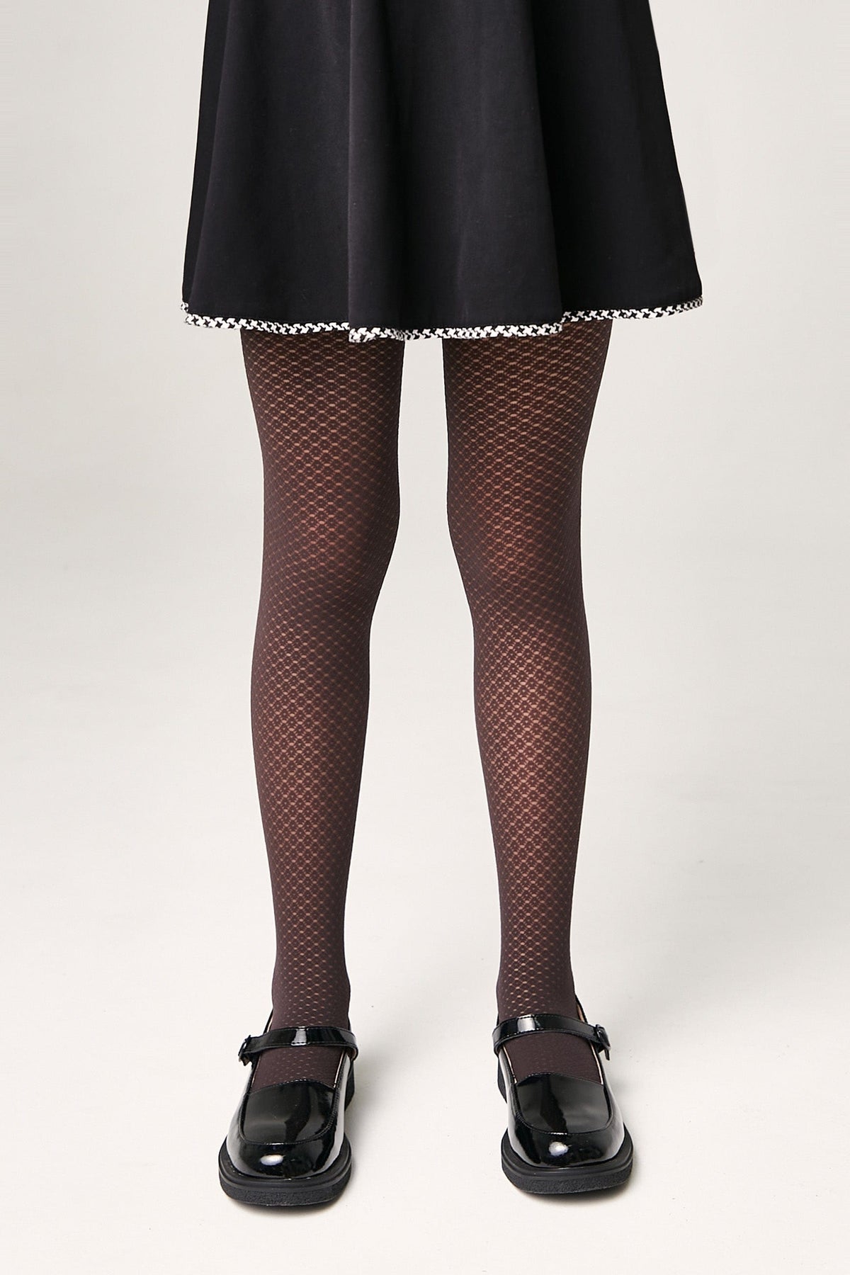 Brown patterned tights worn with a black skirt and black mary jane shoes against a plain white background.