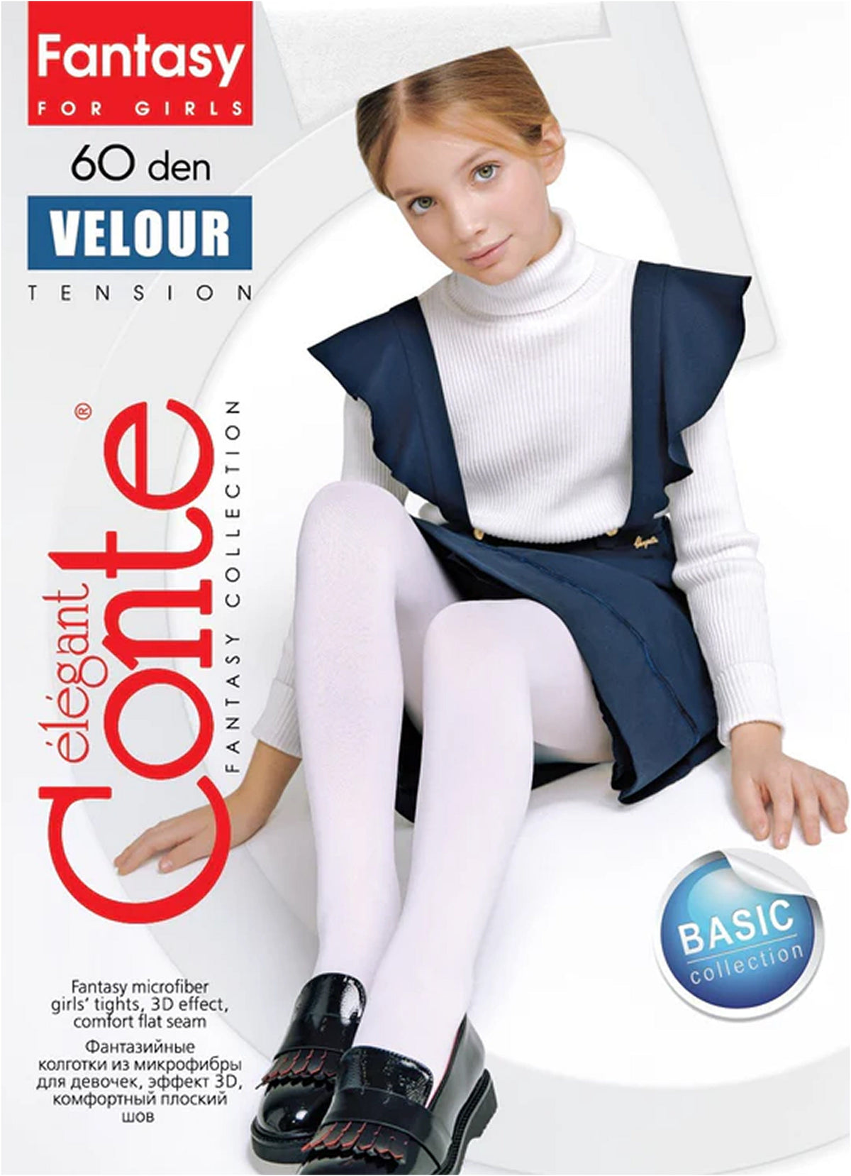 A young girl sits on a white surface wearing white tights, a white turtleneck sweater, and a navy blue pinafore dress with black shoes.