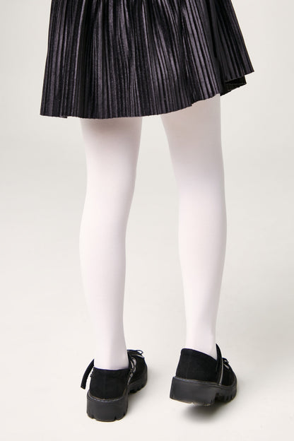 A person wears a pleated black skirt, opaque white tights, and black shoes with side straps.