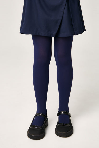 A pair of opaque navy blue tights worn with a navy blue skirt and black Mary Jane shoes.