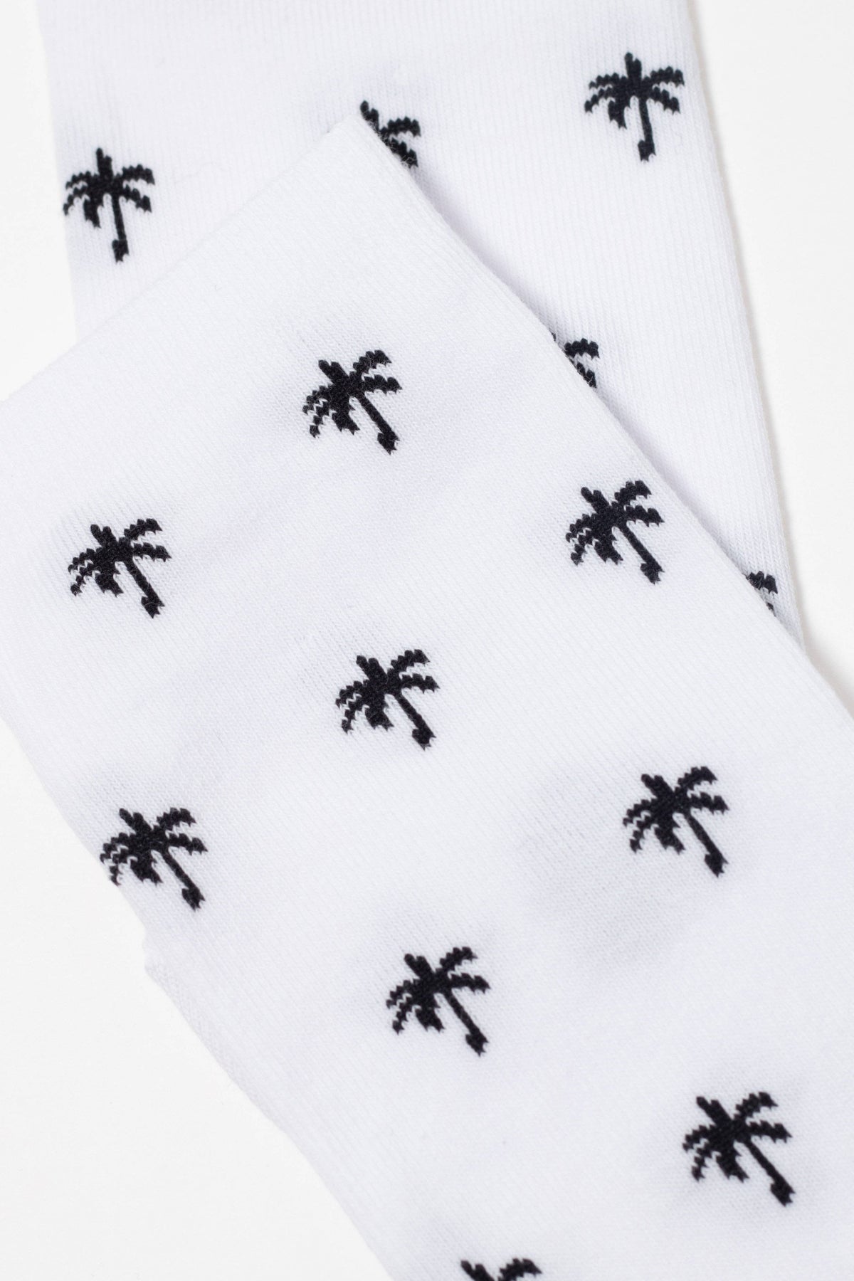 A pair of white crew socks patterned with small, repeating black palm tree icons.