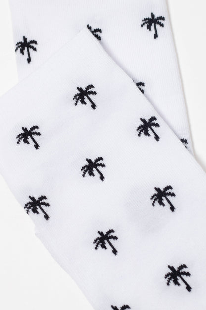 A pair of white crew socks patterned with small, repeating black palm tree icons.