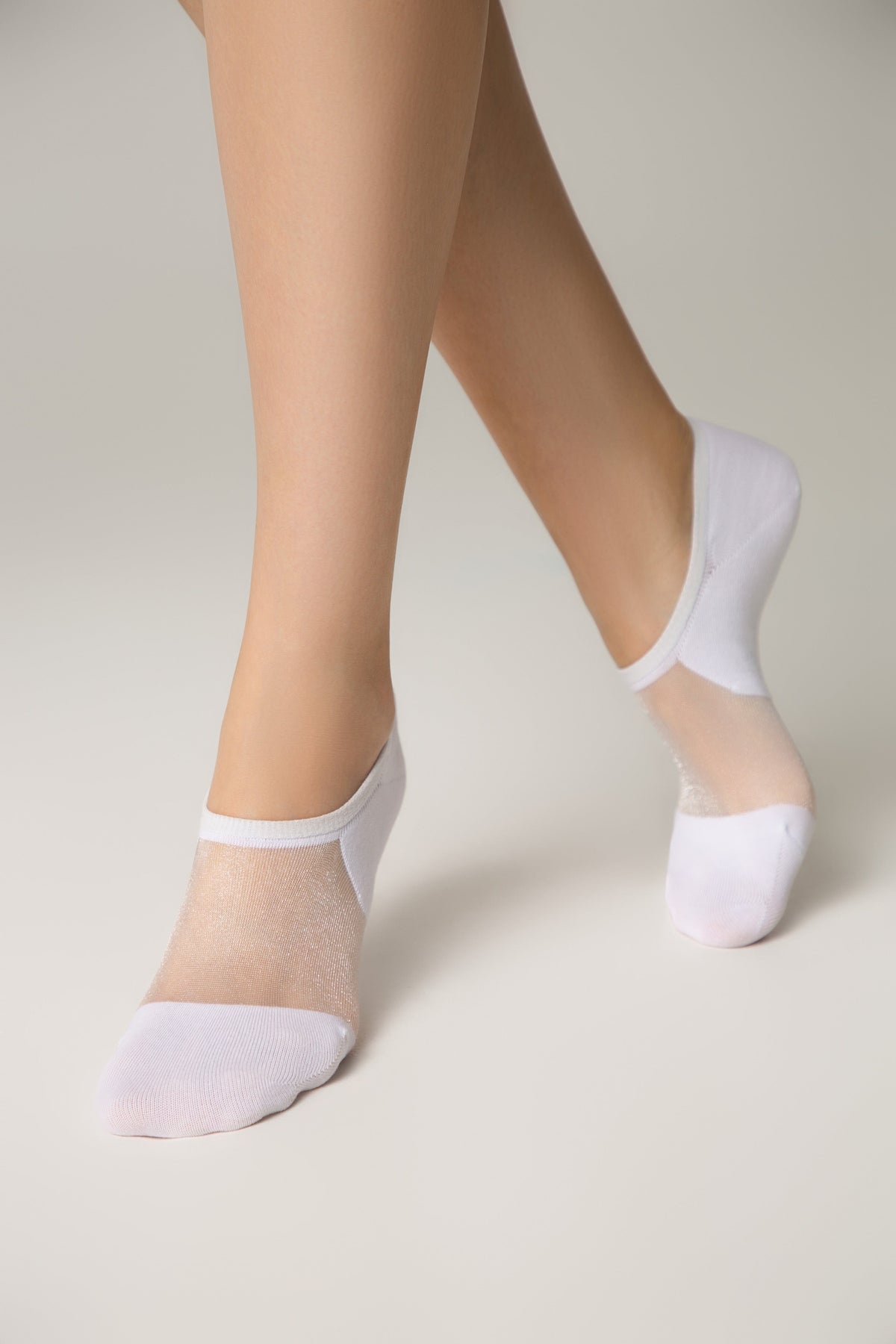 White low-cut socks with a sheer, sparkling mesh top panel worn on a pair of legs against a plain light gray background.
