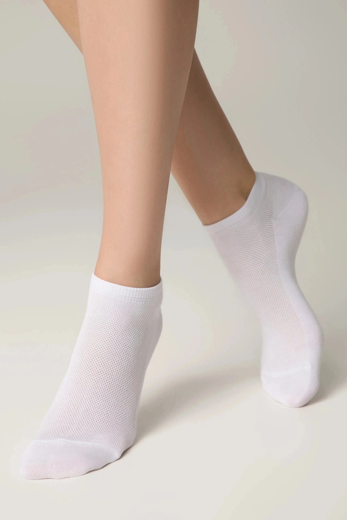 A pair of white ankle socks worn on the feet against a plain light background.