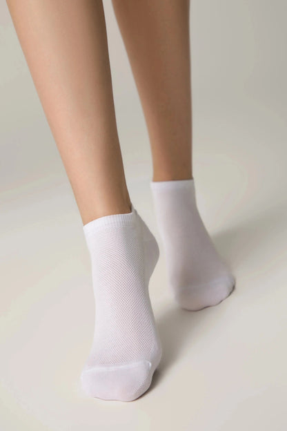 A pair of white ankle socks worn on feet against a plain light background.