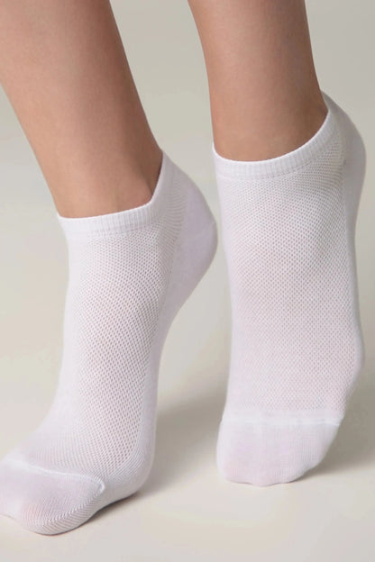 A pair of white ankle socks worn on feet against a solid light background.