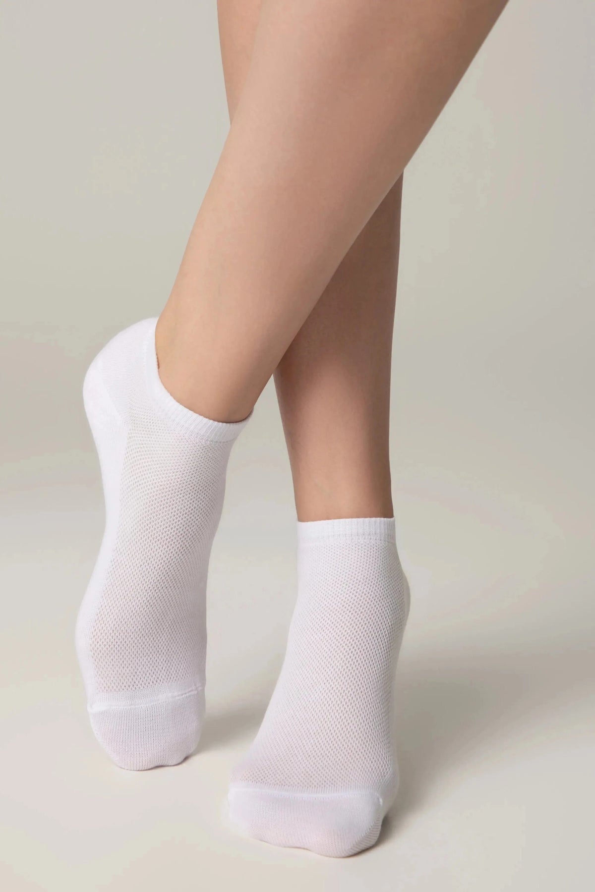 A pair of white ankle socks worn on feet against a neutral background.