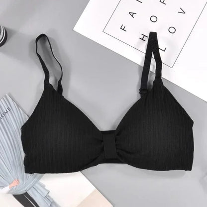 A black ribbed bralette with thin adjustable straps and a center tab detail laying on a grey background.
