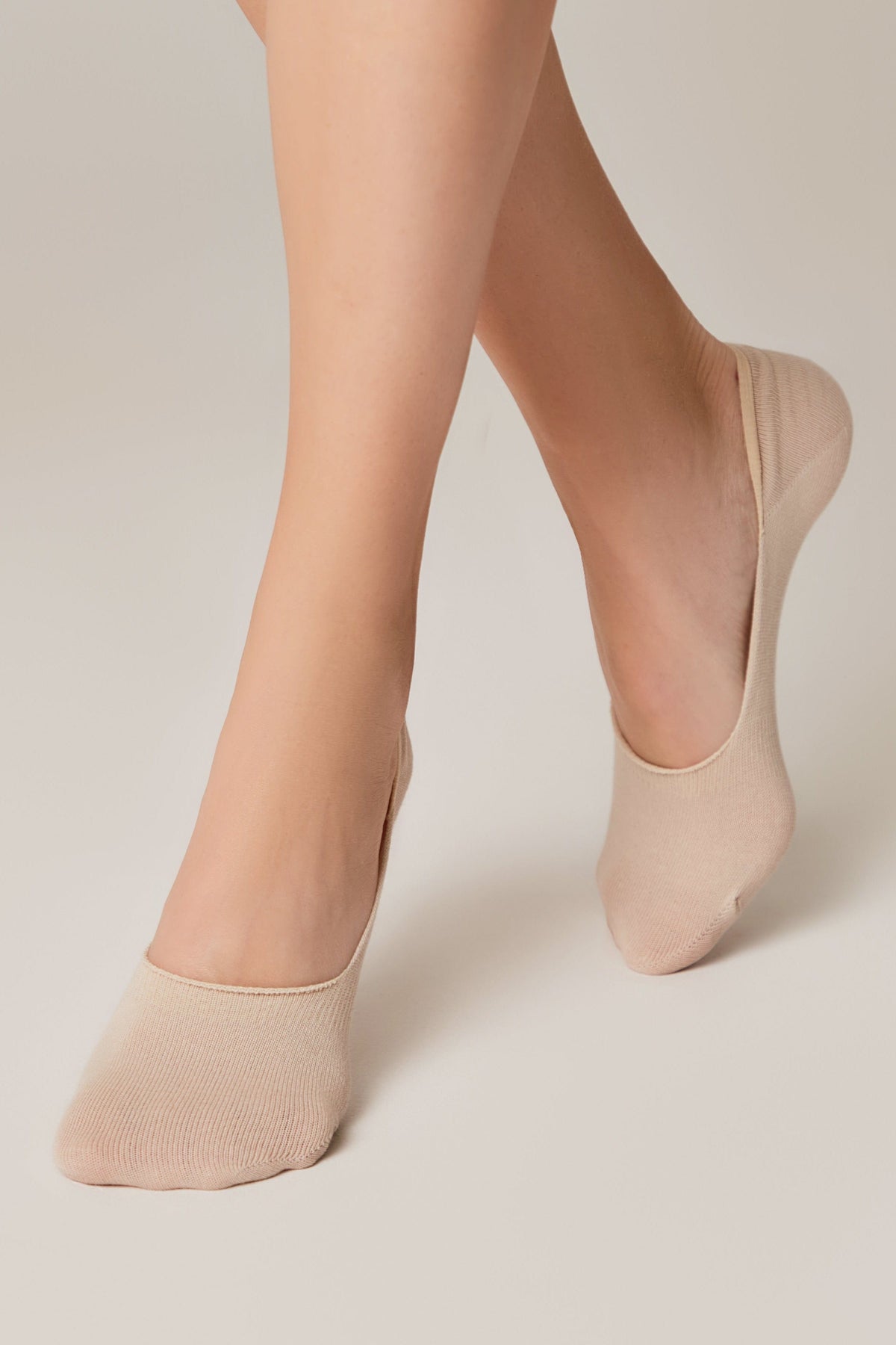 Beige no-show liner socks worn on feet against a solid light background.