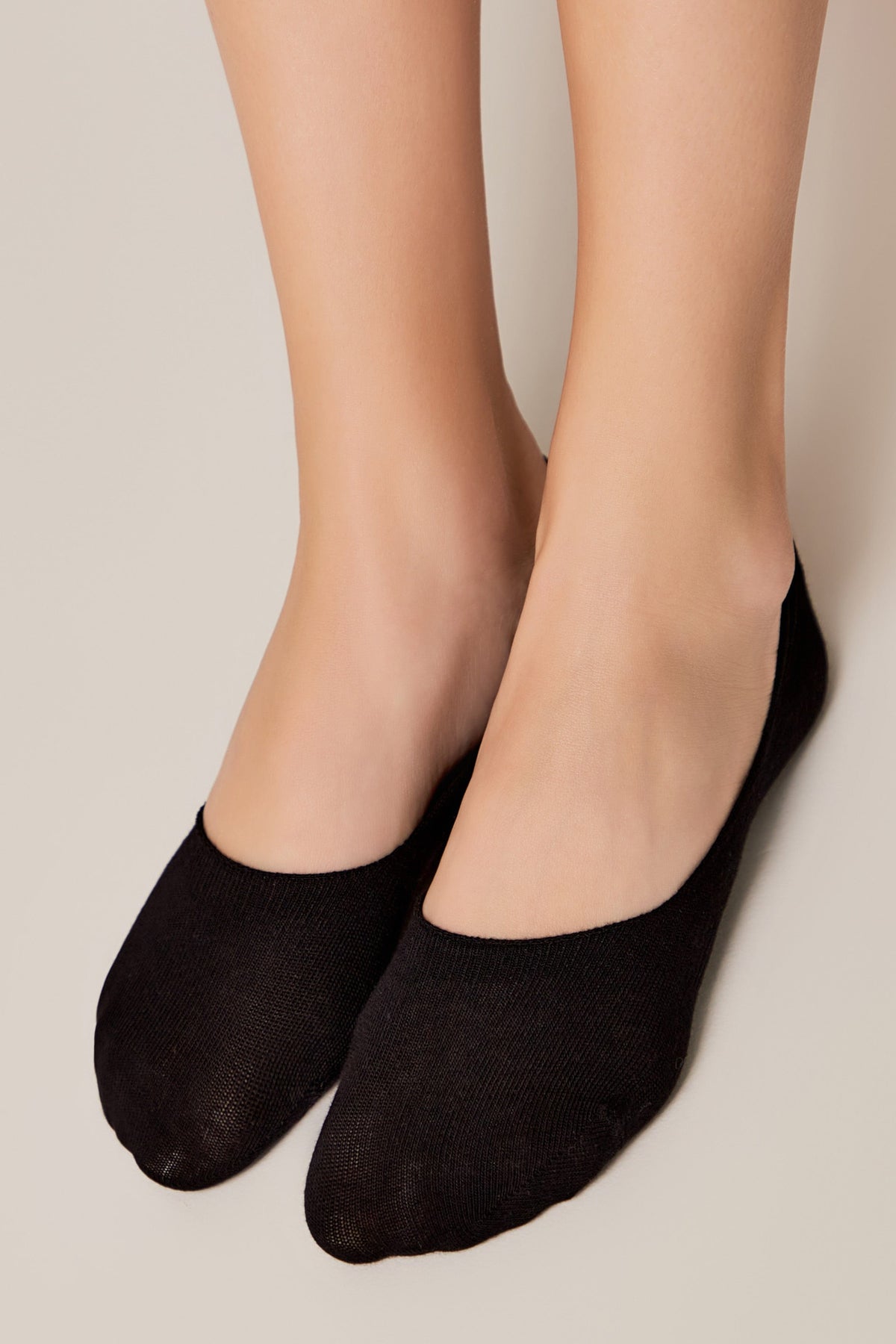 A pair of black no-show socks worn on feet against a neutral background.