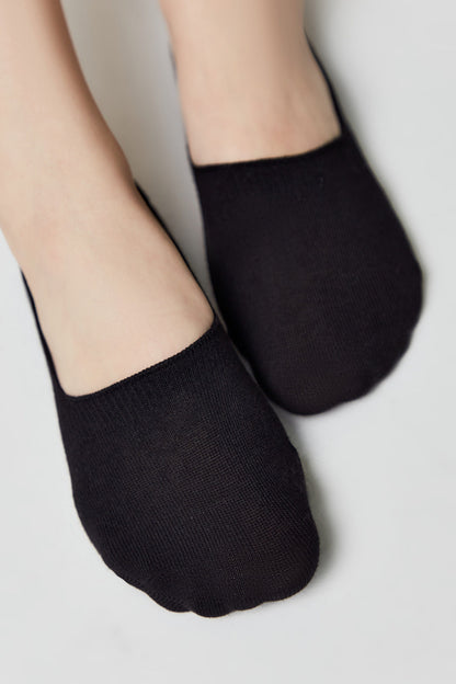 A pair of black low-cut, no-show socks worn on feet against a plain white background.