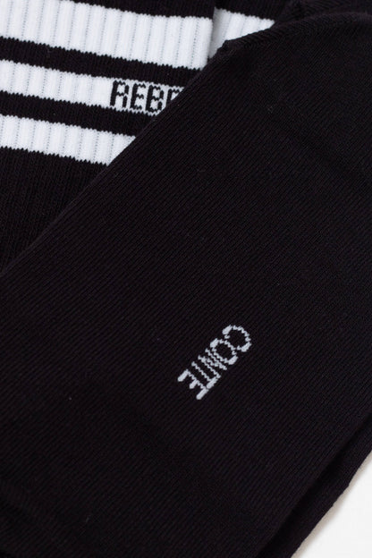 A close-up of a pair of black socks features a white logo with the text CONTE on one side and a ribbed top section with white stripes and partial lettering on the other.