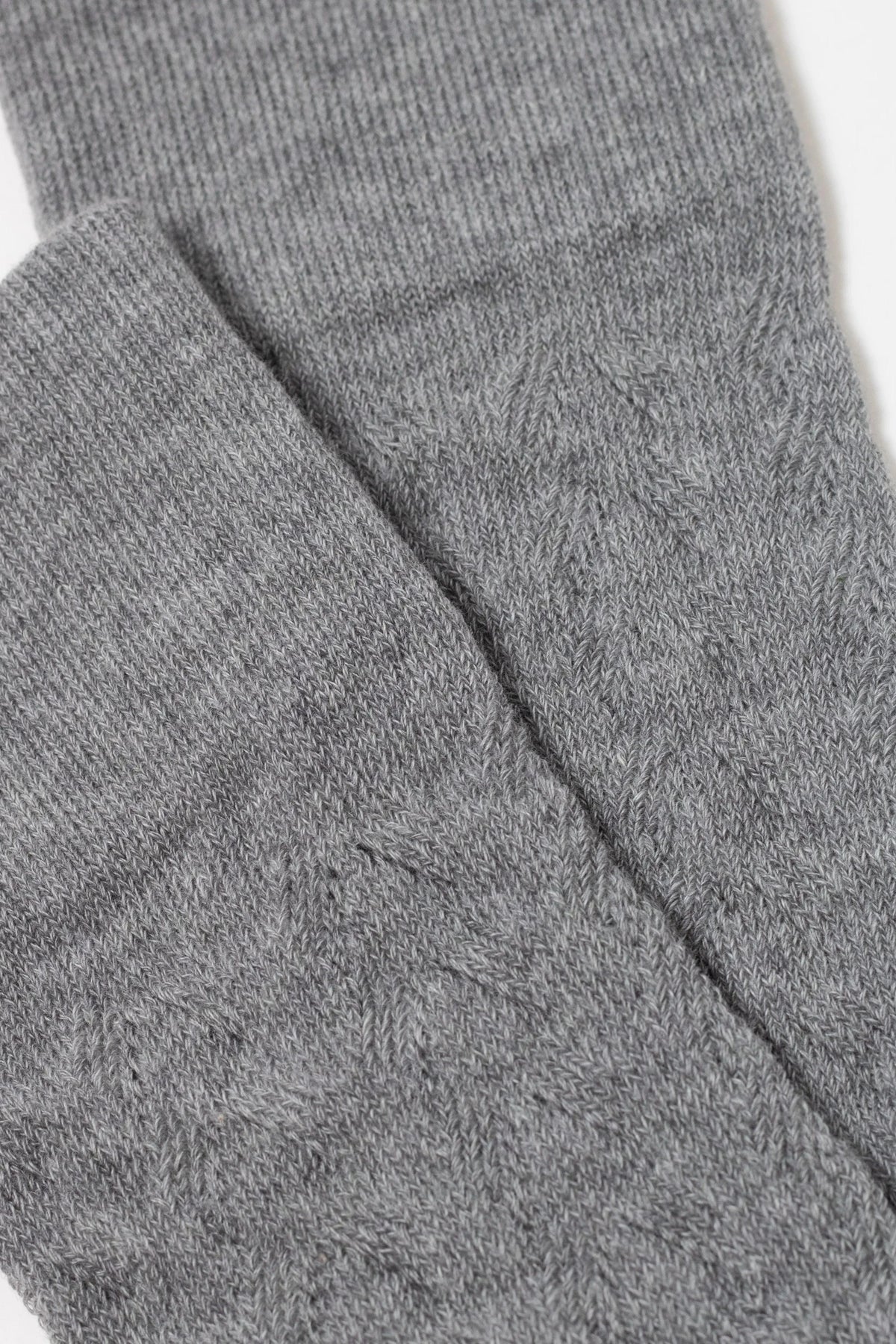 A close-up view shows folded grey fabric with a fine, textured knit pattern.