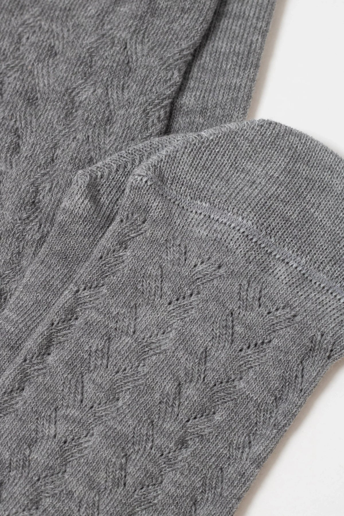 A close-up of a folded pair of grey socks featuring a subtle, raised knitted diamond pattern.