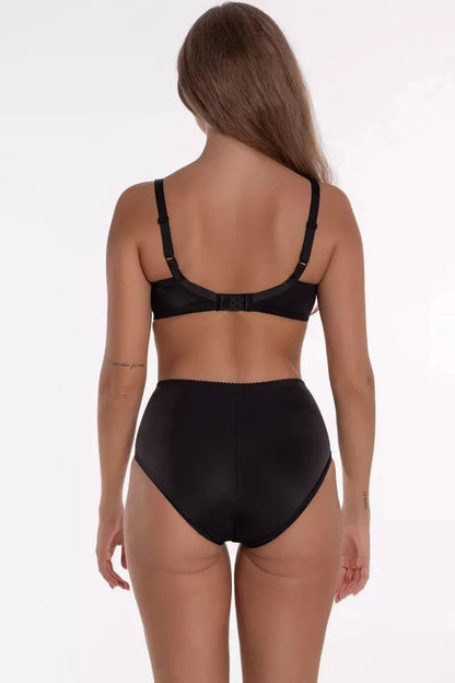 A woman stands facing away from the camera wearing a plain black brassiere and matching high-waisted black briefs against a white background.