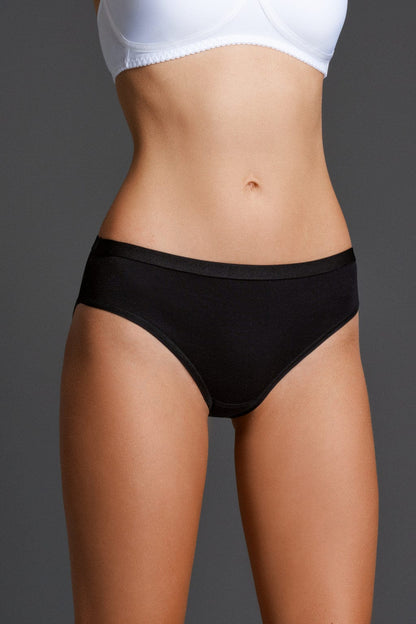 A pair of black bikini-style panties with a plain waistband worn by a person against a solid grey background.