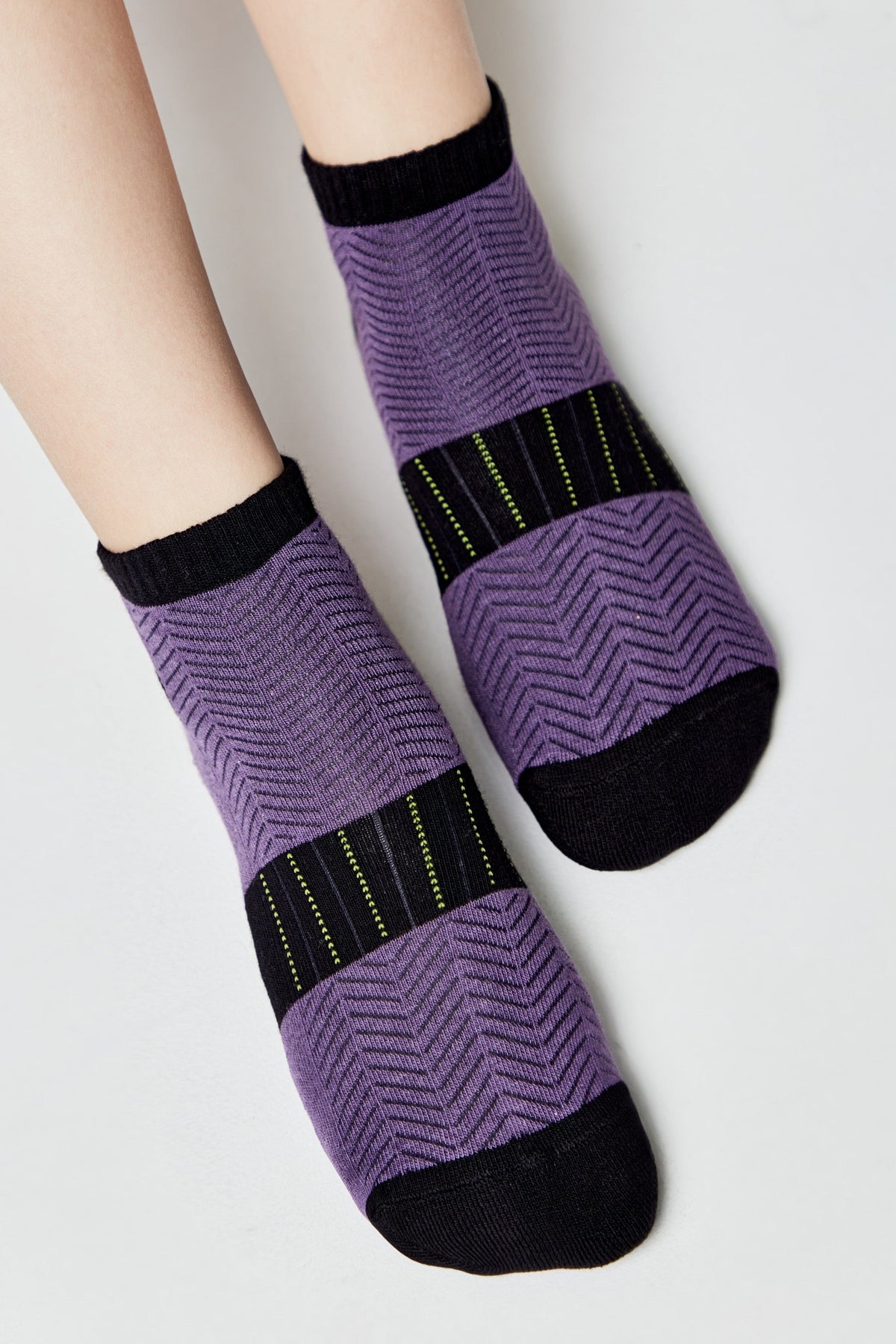 Ankle-length socks featuring a purple herringbone pattern, black trim at the cuffs and toes, and a band of vertical black and yellow stripes across the middle.