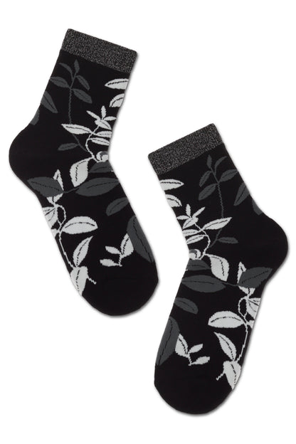 A pair of black crew-length socks featuring a pattern of grey and white leaves throughout, finished with a subtle shimmering grey trim at the cuffs.