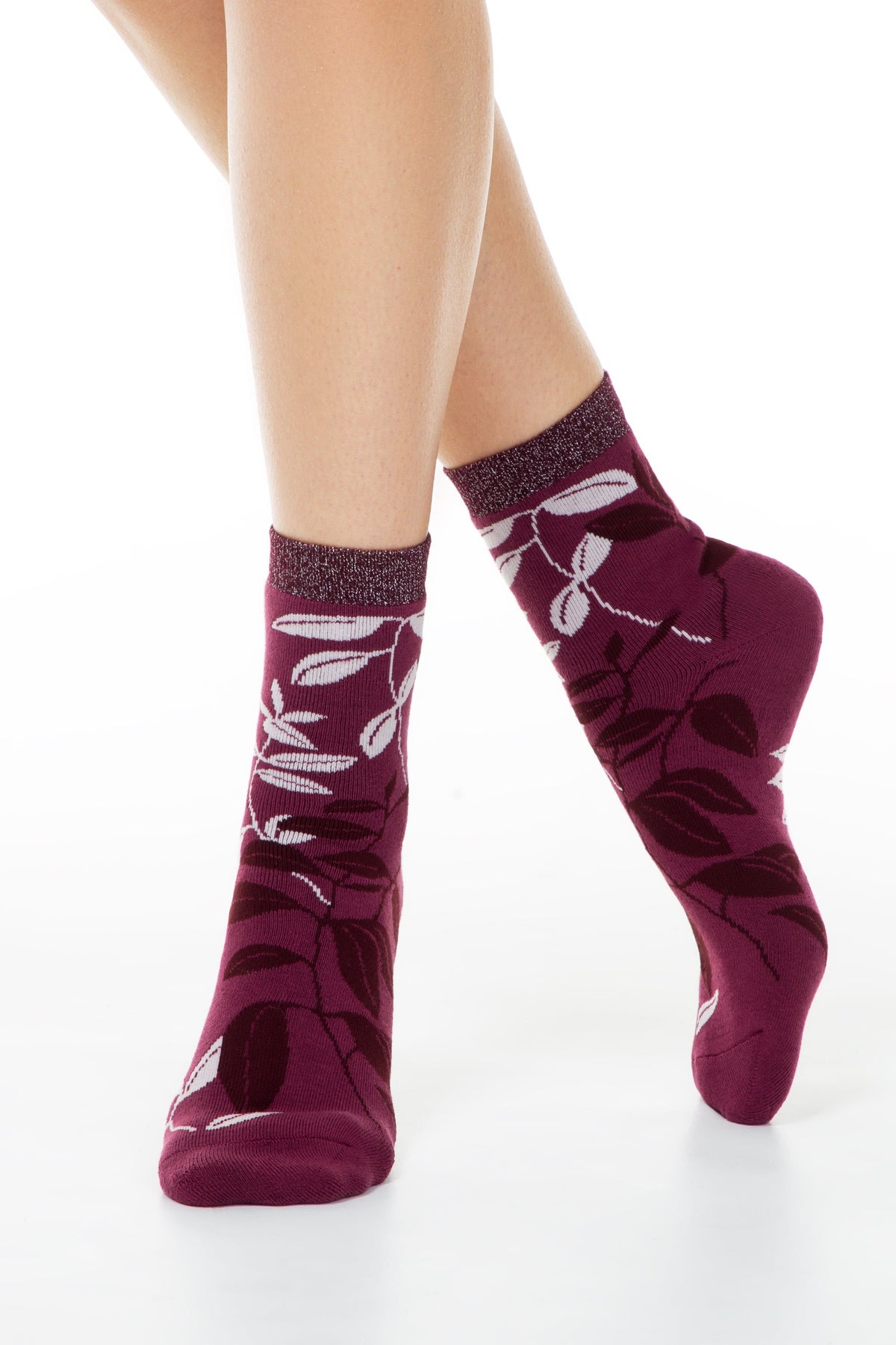 A pair of purple crew socks featuring a white and dark purple leaf pattern, worn by a person against a white background.