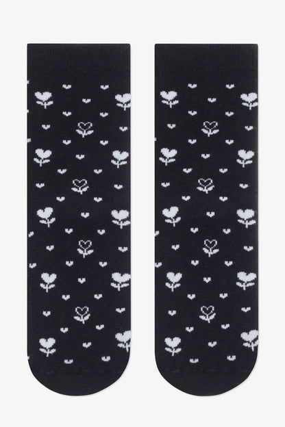 A pair of black ankle socks featuring a repeating pattern of small white heart-shaped flowers and tiny dots.