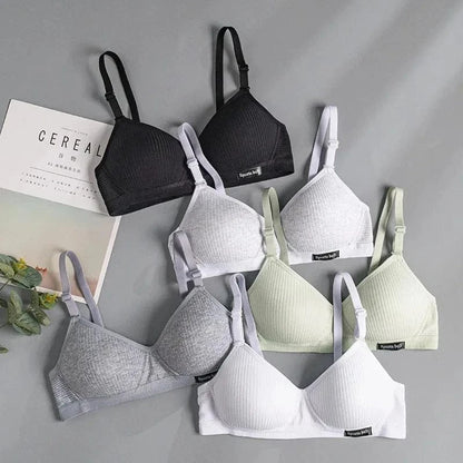 A flat lay of six ribbed triangle bralettes featuring adjustable straps and a small rectangular tag labeled Sports belt, arranged in black, white, grey, and light green on a grey background.
