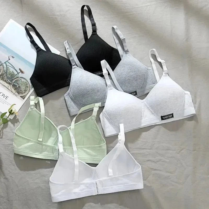 A collection of six seamless triangle bralettes in black, grey, white, and light green arranged on a light-colored fabric background.