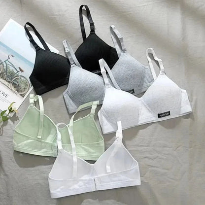 A collection of six seamless triangle bralettes in black, grey, white, and light green arranged on a light-colored fabric background.