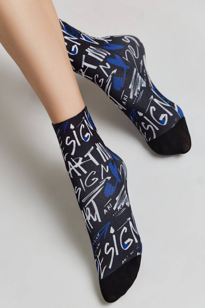 A pair of black ankle socks featuring a white and blue graffiti-style print with the word design repeated across the fabric.