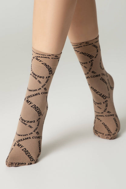 Tan crew-length socks with the repeating black text "MY DREAMS COME TRUE" worn on a person's legs against a neutral background.