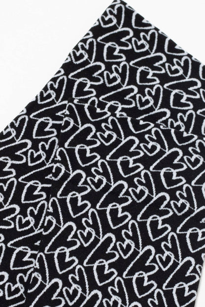 A close-up view of a black fabric featuring a repeating white hand-drawn heart pattern.