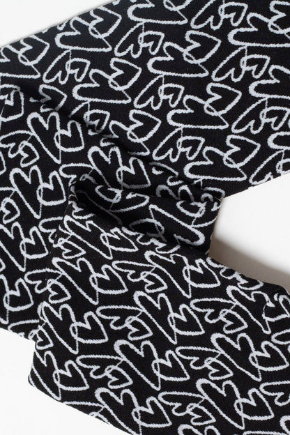 A black fabric with a repeating white hand-drawn heart pattern folded against a plain white background.