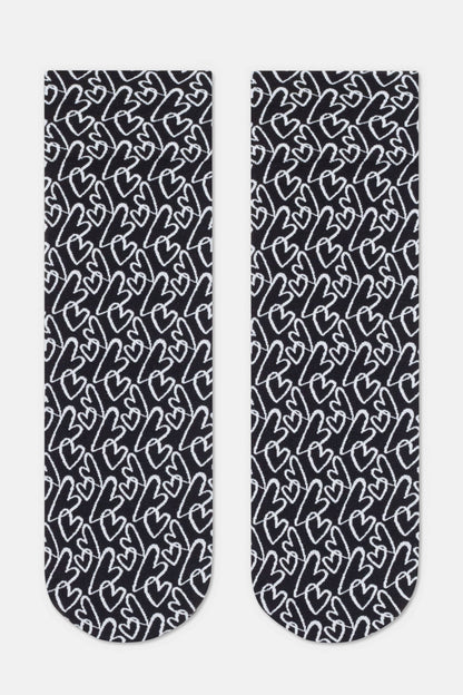 A pair of crew-length socks in black with an all-over repeating pattern of white hand-drawn heart outlines.