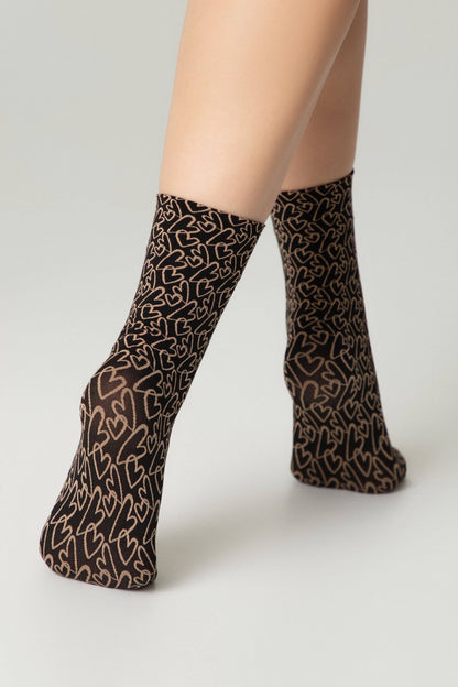 Ankle socks featuring a brown and black heart pattern worn on a person's legs against a plain light gray background.