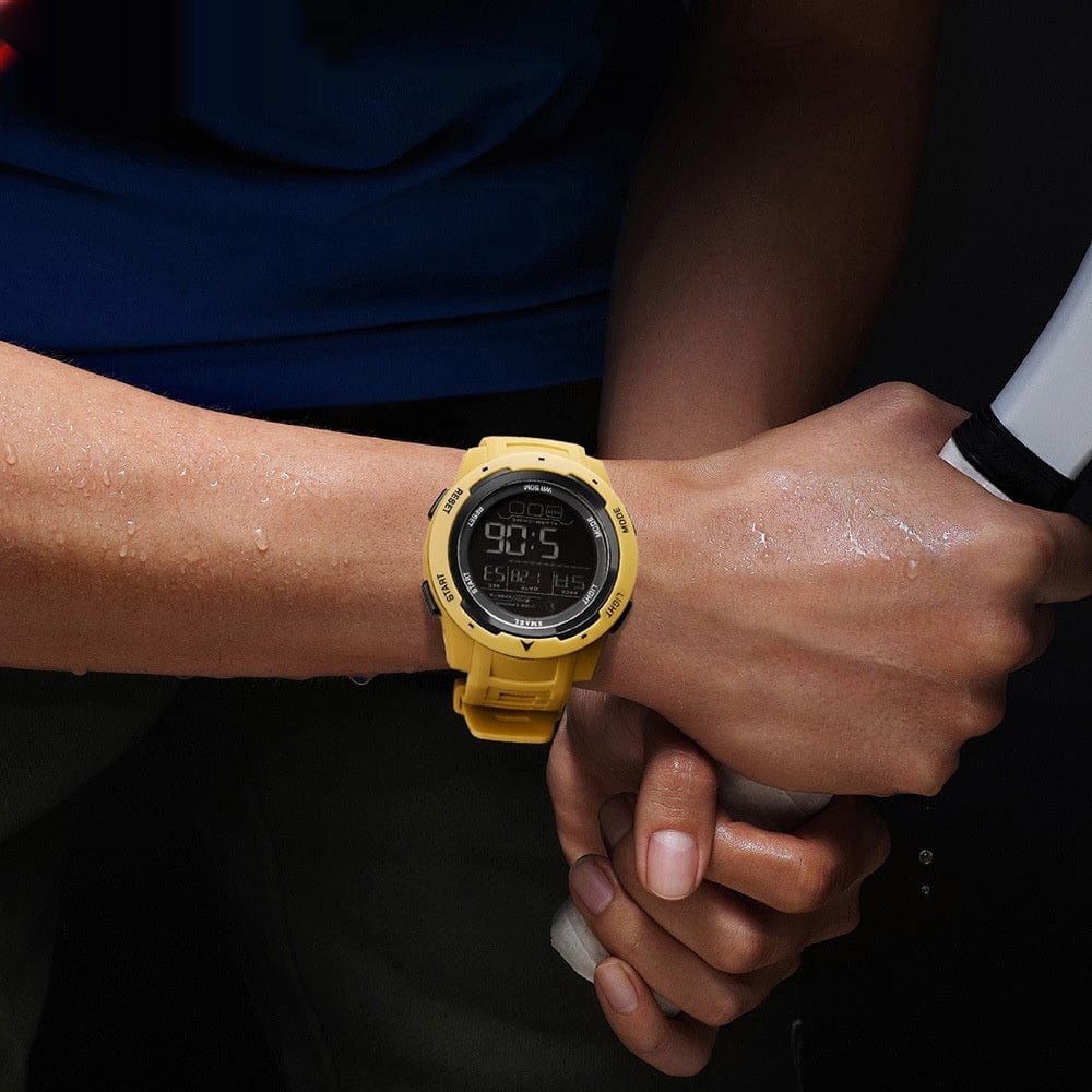 A yellow digital wristwatch worn on a person's wrist against a dark background while holding a handle.
