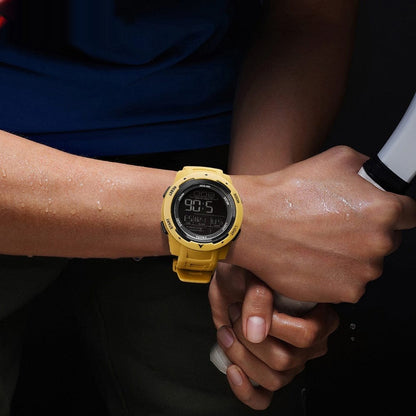 A yellow digital wristwatch worn on a person's wrist against a dark background while holding a handle.
