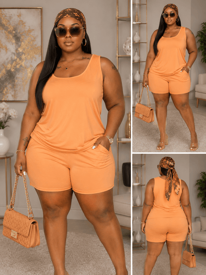 A woman models an orange sleeveless tank top and matching shorts set, accessorized with a patterned headscarf, sunglasses, gold jewelry, and a quilted tan handbag.